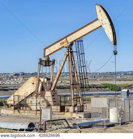 Square Bolsa Chica Ecological Reserve With Steel Oil Rig On Land Against Blue Sky