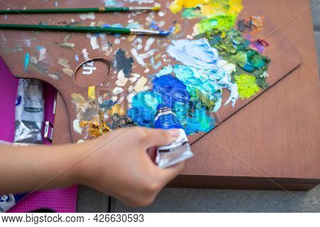 Palette With Multi-colored Paints And Brushes, Woman Painting Picture. High Quality Photo