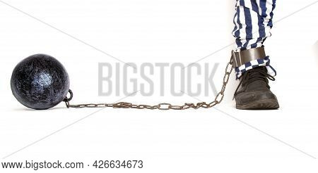 A Leg Of A Prisoner In Striped Pants And A Rough Boot Chained With An Iron Ball With Shackles In Pro