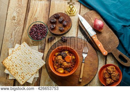 Jewish Dish Chelnt With Meat In A Plate On A Wooden Table On A Stand Next To Ingredients. Horizontal