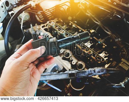 Ignition Coil For Spark Plug Of The Car Ignition System In The Mechanic Hand With A Car Engine Blurr