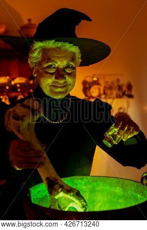 Old Woman Disguised As A Witch On Halloween Preparing With Cow Bones And Salt A Magic Potion In Her 