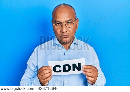 Middle age latin man holding cdn message paper relaxed with serious expression on face. simple and natural looking at the camera. 