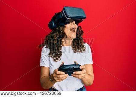 Middle age woman wearing virtual reality glasses playing 3D videogames, watching futuristic simulation, excited experience