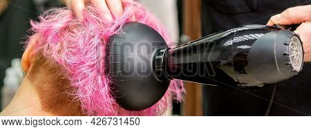 A Male Hairdresser Professional Drying Stylish Pink Hair Of The Female Client With A Blow Dryer In A