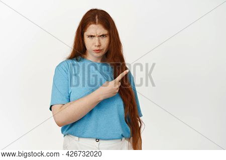 Angry Teen Redhead Girl, Furrow Eyebrows And Pointing At Upper Right Corner With Displeased Uspet Fa