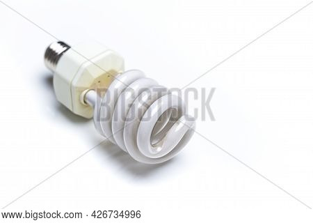 Energy Saving Concepts. Closeup Image Of Used Energy-saving Fluorescent Light Bulb Against White Bac