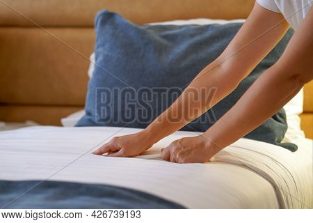 Hands Of Woman Maid Making Bed In Hotel Room. Housekeeper Making Bed