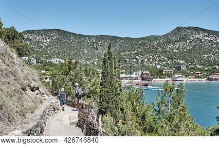 A Boy And A Man Hiking On The Scenic Golitsyn Trailover Background Of The Sea Bay And The Village Of