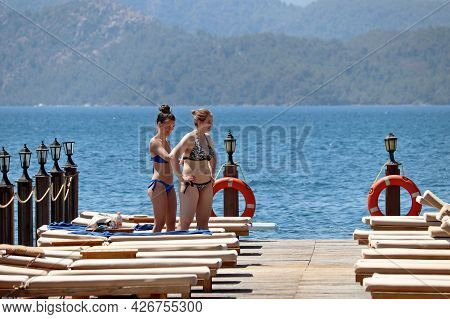 Hisaronu, Turkey - July 2021: Two Happy Girls Apply Sunscreen To Each Other On A Beach On Mountains 