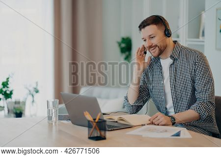 Horizontal Shot Of Cheerful Man Participates In Self Improvement Webinar Wears Checkered Shirt Commu