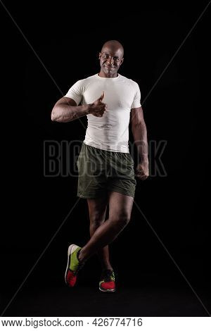Black Man Standing Looking At Camera With Thumb Up And One Leg Crossed