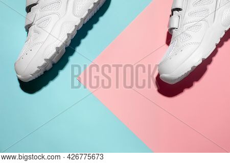 Top View Two White Sneakers On A Delicate Geometric Paper Pink And Blue Background With Hard Sunligh