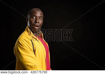 Side View Of An African American Man Standing Looking At Camera Black Background