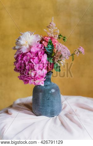 Flowers in a vase by a yellow wall