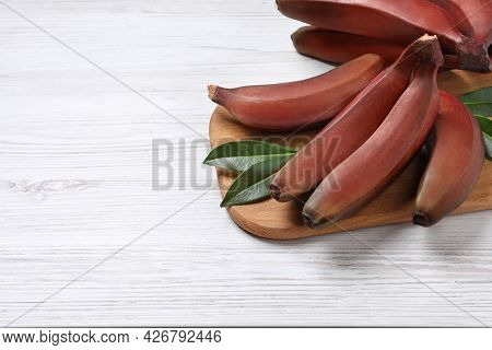 Tasty Red Baby Bananas On White Wooden Table, Space For Text