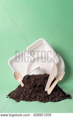 Various Single-use Tableware Non-plastic Alternative In Ground Heap On Green Background, Vertical. W