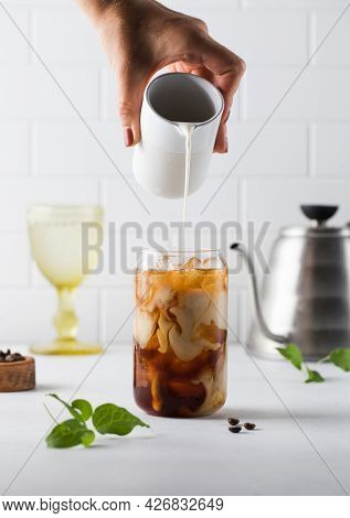 Cream Is Poured Into Cold Black Coffee With Ice Cubes. Coldbrew. Summer Drinks.