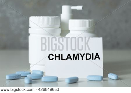 On The Business Card Is The Text Of Chlamydia, Next To The Blue Capsules, White Medicine Jars In The