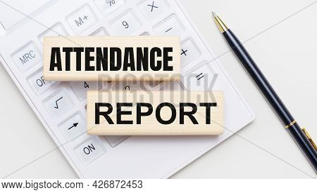 Wooden Blocks With The Text Attendance Report Lie On A Light Background On A White Calculator. Nearb