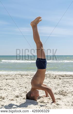 The Guy Is Doing Yoga On The Beach. On The Shore Of The Ocean.