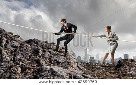 Imagem de busionessman e empresária puxando a corda no topo da montanha