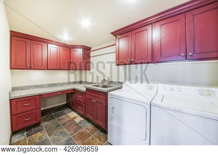 Laundry Room Interior With Burgundy Drawers And Wall Cabinets
