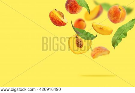 Flying Fresh Ripe Juicy Peaches With Green Leaves On Yellow. Whole And Halved Peaches With Pits, Sli