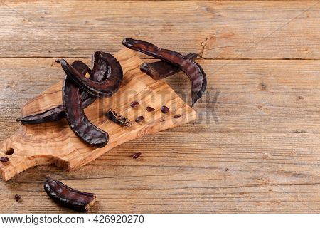 Dry Raw Carob Pods On Wooden Background