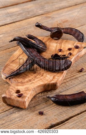 Dry Raw Carob Pods On Wooden Background