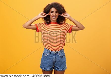 What That Anoying Sound. Disturbed And Displeased Dark-skinned Girl With Curly Hair Frowning Clenchi