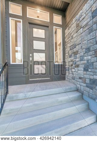 Vertical Home Facade With Stone Brick Wall And Gray Front Door With Frosted Glass Panels