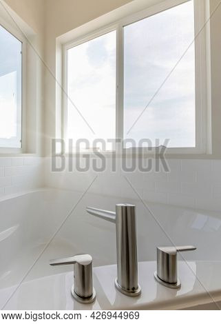 Vertical Corner Bathtub In A Bathroom With Widespread Faucet Against The Windows