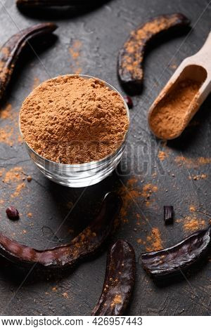 Dry Carob Pods And Carob Powder Over Dark Background