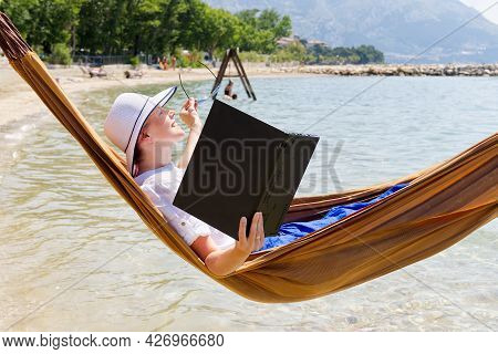 Work From Anywhere. Young Smilyng Woman, Female Freelancer In Straw Hat Working On Laptop On Beach.