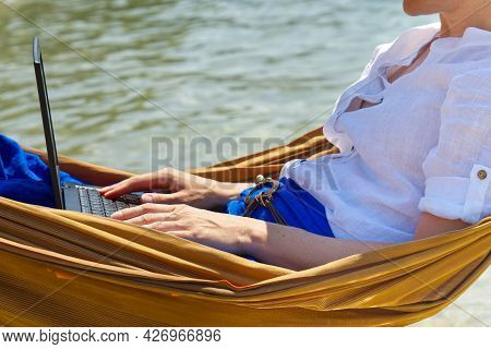Work From Anywhere. Young Smilyng Woman, Female Freelancer In Straw Hat Working On Laptop On Beach.