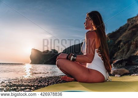 Young Woman With Long Hair In White Swimsuit And Boho Style Braclets Practicing Outdoors On Yoga Mat