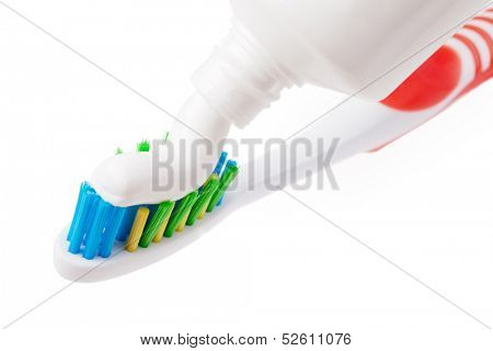 Squeezing toothpaste onto toothbrush, on a white background