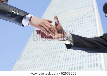 Close-up of two business people shaking hands by the World Trade Center in Beijing