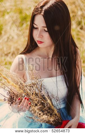 Beautiful brunette girl sitting in a cornfield