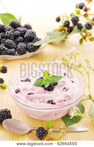 Bowl with blackberry yogurt with fresh blackberries on wood