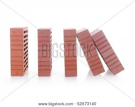 Line of red bricks with the first brick falling over the next one making a domino effect shot over white