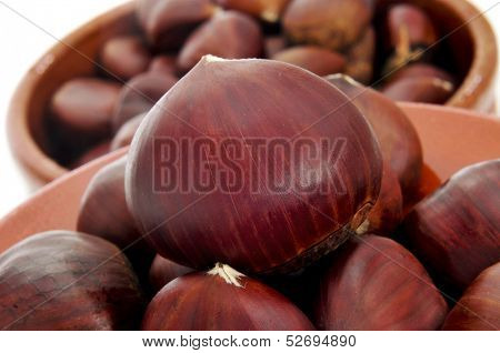 closeup of some chestnuts in earthenware bowls on a white background
