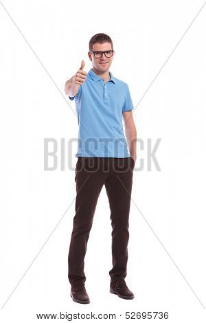 full length picture of a young casual man showing the thumb up gesture while holding a hand in his pocket. on white background