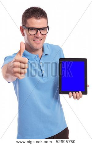 young casual man presenting his tablet and showing the thumb up gesture to the camera. on white background