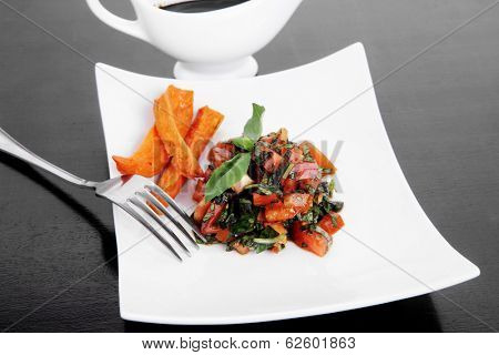 vegetable salad : cherry tomatoes and basil with sweet baked potato served on white plate with sauce boat full blask soy sauce on wood