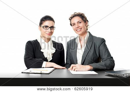 Two young beautiful businesswoman sitting at frontdesk