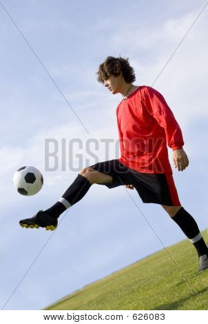 Fotbal - fotbalový záložník žonglování v červené barvě
