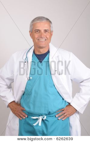Usmívající se středním věku lékař v laboratorní plášť a křoviny