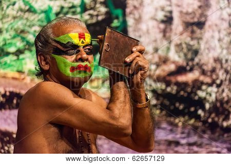KOCHI, INDIA - FEBRUARY 24, 2013: Unidentified Kathakali exponent preparing for performance by applying face make-up. Kathakali is the classical dance form of Kerala